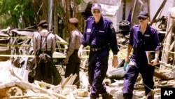 Dalam foto tertanggal 17/10/2002 ini polisi Indonesia dan tim forensik Australia melakukan pemeriksaan di lokasi ledakan di Kuta, Bali , setelah terjadi serangan bom pada 12/10/2002. 