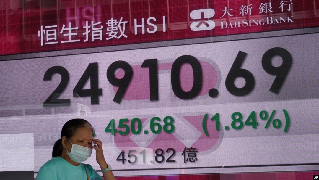 A woman walks past a bank's electronic board showing the Hong Kong share index at Hong Kong Stock Exchange, Nov. 3, 2020. 