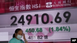 A woman walks past a bank's electronic board showing the Hong Kong share index at Hong Kong Stock Exchange, Nov. 3, 2020. 