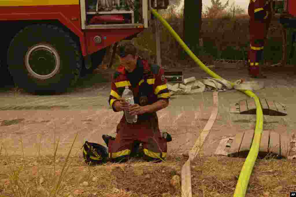 A firefighter from Slovakia cools himself down during a wildfire in Avgaria village on Evia island, about 184 kilometers (115 miles) north of Athens, Greece.