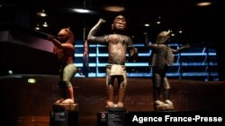 FILE - A visitor looks at statues of the 'Royal treasures of Abomey kingdom' on display at the Musee du quai Branly in Paris on Sept. 10, 2021, part of 26 artworks set to be restituted to Benin later in the year. 