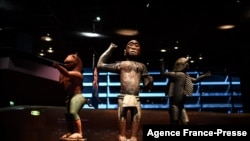 Un visiteur regarde les statues des "trésors royaux du royaume d'Abomey" exposées au musée du quai Branly à Paris le 10 septembre 2021. Elles font partie des 26 oeuvres d'art qui ont été restituées au Bénin en novembre 2021.