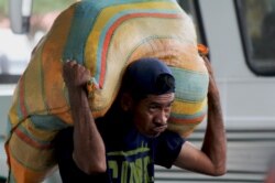 A man carries a load on his back as he works as a “lomo taxista,” or taxi of the lower back, outside a bus terminal in San Antonio, Venezuela, Sept. 19, 2019.