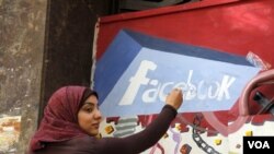 Seorang mahasiswi Universitas Helwan menggambar 'mural' Facebook di salah satu tembok di Kairo sebagai peringatan revolusi melengserkan Hosni Mubarak yang diorganisir melalu Facebook dan Twitter.