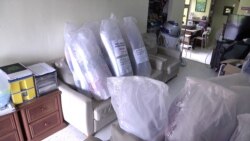 Face shields bound for Malaysian hospitals are stacked up on the chairs and sofas in Alvisse’s living room. (VOA/Dave Grunebaum)