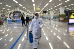 FILE - A State Commission of Quality Management staff member carries a disinfectant spray can as checks are done to inspect and quarantine goods being delivered via the borders at the Pyongyang Airport in Pyongyang, North Korea, Feb. 1, 2020.