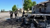 Сотрудники украинской полиции осматривают сгоревшие автомобили на месте удара в селе Золочев Харьковской области, 1 мая 2024 года 