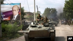 FILE - Ossetian soldiers sit on top of an armored personnel carrier entering Tskhinvali, the capital of Georgian breakaway enclave of South Ossetia, on Aug. 11, 2008, next to a portrait of then-Prime Minister Vladimir Putin and inscription in Cyrillic: Putin is our President.