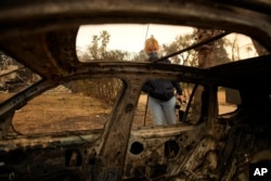 Lissa Renn looks at the remains of a car in Altadena, California, Jan. 9, 2025.