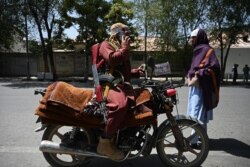 FILE - A Taliban fighter sits on his motorcycle along a roadside at Shahr-e Naw in Kabul on Aug. 16, 2021.