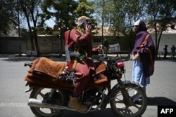 FILE - A Taliban fighter sits on his motorcycle along a roadside at Shahr-e Naw in Kabul on Aug. 16, 2021.