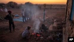 Warga yang melarikan diri dari konflik di wilayah Tigray Ethiopia membakar kayu untuk menyiapkan makan malam di depan tempat penampungan sementara mereka di kamp pengungsi Umm Rakouba di Qadarif, Sudan timur, 7 Desember 2020. (Foto AP / Nariman El-Mofty)
