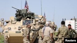 FILE - Kurdish fighters from the People's Protection Units (YPG) chat with members of U.S. forces in the town of Darbasiya next to the Turkish border, Syria, April 29, 2017.