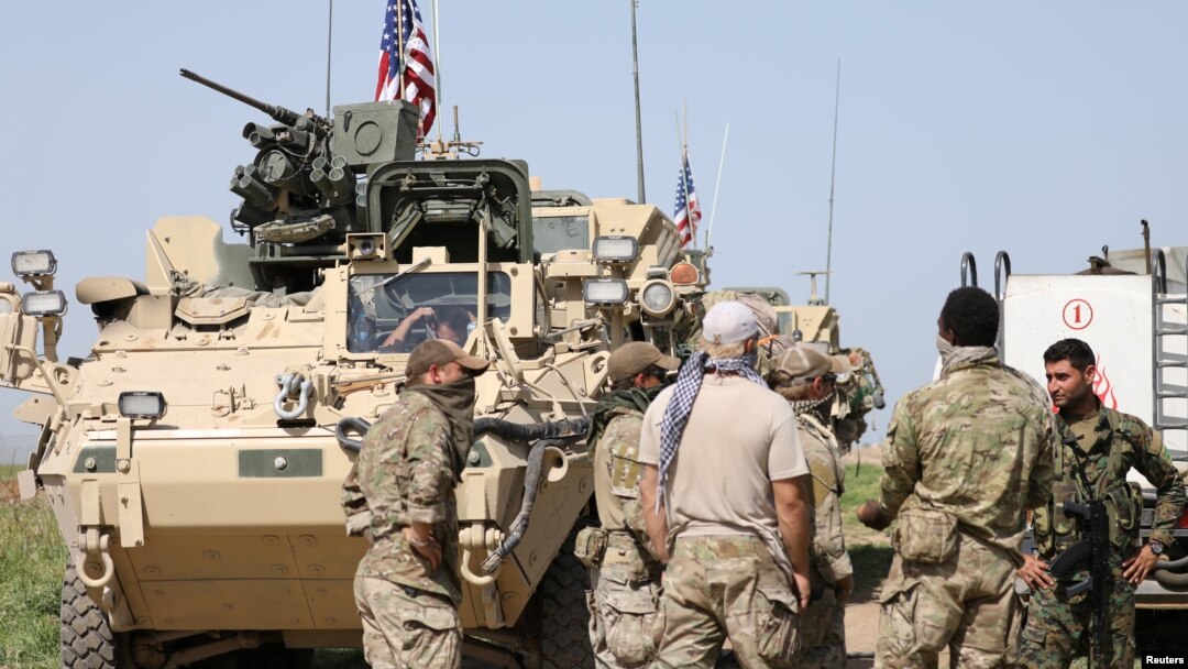 FILE - Kurdish fighters from the People's Protection Units (YPG) chat with members of U.S. forces in the town of Darbasiya next to the Turkish border, Syria, April 29, 2017.