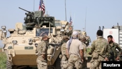 FILE - Kurdish fighters from the People's Protection Units (YPG) chat with members of U.S. forces in the town of Darbasiya next to the Turkish border, Syria, April 29, 2017.