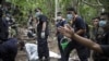Policemen monitor as forensic experts dig out human remains near the abandoned human trafficking camp in the jungle close the Thailand border at Bukit Wang Burma in northern Malaysia May 26, 2015. Malaysian police forensic teams, digging with hoes and sho