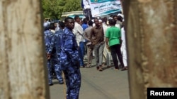 FILE - Policemen (in blue uniforms) keep an eye on protesters during a rally in Khartoum, Sudan, May 22, 2015.