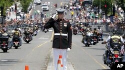 Seorang perwira Angkatan Laut memberikan penghormatan kepada para pengendara sepeda motor yang melintas di jalan saat parade tahunan 'Rolling Thunder' memperingati Memorial Day di Washington (27/5).