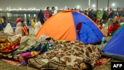 A Hindu pilgrim sleeps near Sangam, the confluence of the Ganges, Yamuna and mythical Saraswati rivers, during the Maha Kumbh Mela festival in Prayagraj on January 13, 2025.