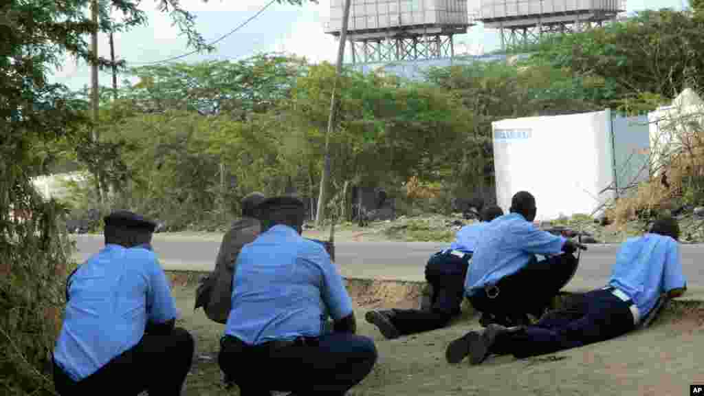 Agentes da polícia se protegem atrás de cobertura durante ataque armado na universidade.