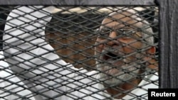 Muslim Brotherhood leader Mohammed Badie shouts slogans from the defendant's cage during his trial with other leaders of Brotherhood in a courtroom in Cairo, Dec. 11, 2013.