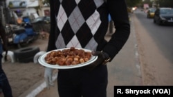 Seorang pria membagikan kurma kepada pengemudi taksi dan penumpang bus di sepanjang jalan yang sibuk di Dakar, Senegal, 23 Mei 2018, saat matahari terbenam dan saatnya berbuka puasa selama Ramadan. (Foto: VOA)