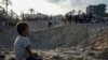 FILE - Palestinians look at the destruction after an Israeli airstrike on a crowded tent camp housing Palestinians displaced by the war in Muwasi, Gaza Strip, Sept. 10, 2024.