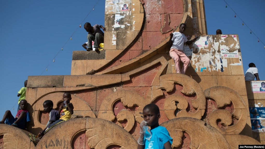 Crianças brincam num monumento de Bissau