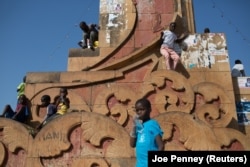 Crianças brincam num monumento de Bissau, capital da Guiné-Bissau.