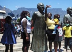 People take photos at a statue of Anglican Archbishop Desmond Tutu at the V&A Waterfront in Cape Town, South Africa, Sunday, Dec. 26, 2021.(AP)