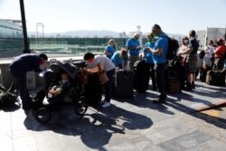 Los voluntarios ayudan a los viajeros mientras esperan un vuelo chárter organizado por la embajada de EE. UU., ya que la COVID-19 continúa propagándose en Guatemala.