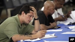Job seekers fill out applications at a construction job fair in New York, August 21, 2012.