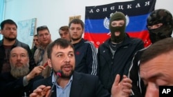 Denis Pushilin, foreground center, spokesman of the self-appointed Donetsk People’s Republic, speaks to reporters inside the regional administration building seized earlier in Donetsk, Ukraine, April 18, 2014.