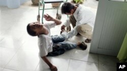 Nạn nhân nhiễm chất da cam Lê Văn Tâm, 14 tuổi, được cha săn sóc tại trung tâm phục hồi chức năng ở Đà Nẵng, Việt Nam