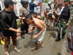 Petugas polisi dan tentara mengawasi narapidana yang dievakuasi dari Penjara Kabanjahe di Kabanjahe, Sumatra Utara, Rabu, 12 Februari 2020.