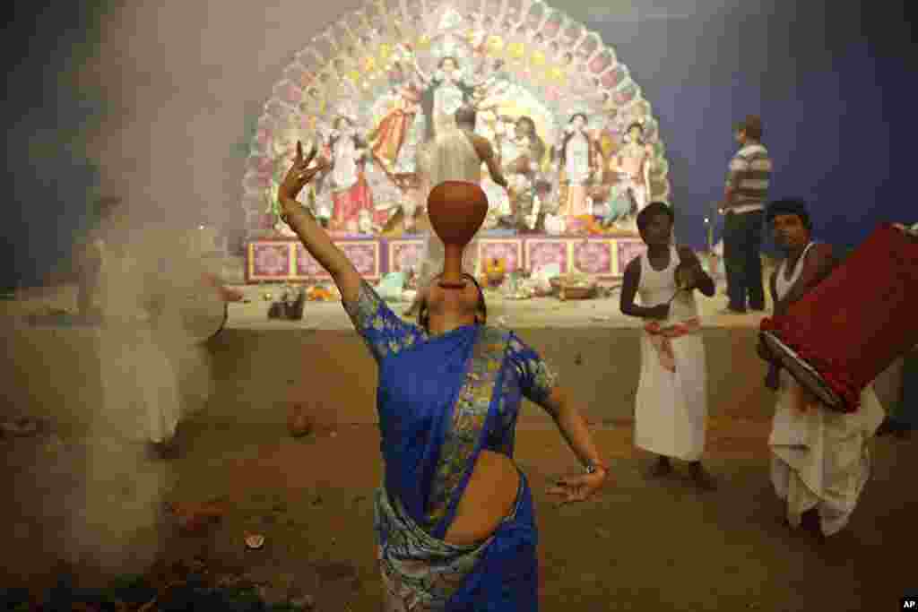 A Hindu devotee performs a traditional Dhunuchi dance inside a temporary worship venue of goddess Durga during the Durga Puja festival in Allahabad, India, Oct. 1, 2014. 