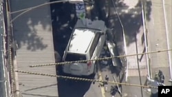 In this photo made video from the Australian Broadcasting Corp., a white SUV vehicle is stopped after allegedly striking pedestrians, Dec. 21, 20217, in Melbourne, Australia. Local media say over a dozen people have been injured after a car drove into pedestrians on a sidewalk in central Melbourne.