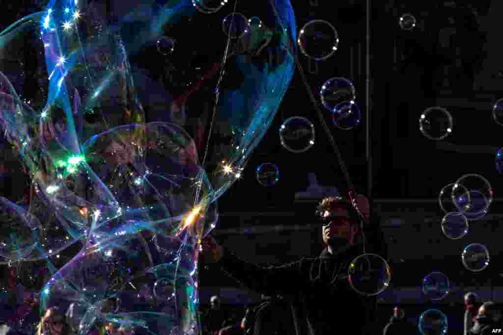 A man blows giant soap bubbles for tourists on Piazza del Popolo in downtown Rome, Italy.