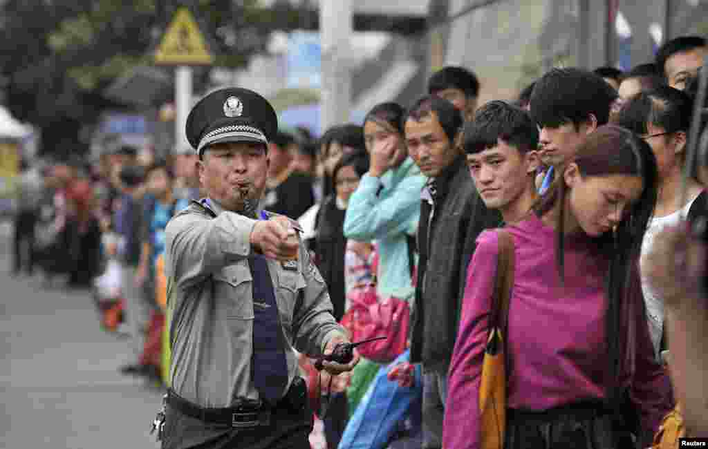 A security guard gestures as he blows a whistle at a bus stop outside the city's railway station, during a traffic peak on the last day of China's National Day Golden Week in Hefei, Anhui province.