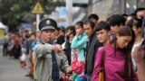 FILE - A security guard blows a whistle at a bus stop outside a railway station Hefei, Anhui province during a busy time, Oct. 7, 2013. (Reuters photo)