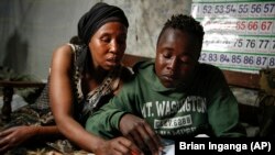 FILE - In this Saturday, Sept. 26, 2020 file photo, Miriam Nyambura helps her son Peter Kihika, 16, who wants to become a teacher.