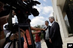 Austin Mayor Steve Adler, right, and Travis County Judge Sarah Eckhardt talk with reporters outside the federal courthouse, June 29, 2017, in Austin, Texas. A new Texas "sanctuary city" ban is back in court as the state asks a federal judge to approve of letting police officers ask people their immigration status during routine stops.