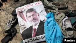 A poster of deposed Egyptian president Mohamed Morsi lies amid debris in a cleared protest camp of his supporters in Cairo August 15, 2013.