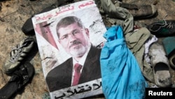 A poster of deposed Egyptian president Mohamed Morsi lies amid debris of a cleared protest camp of his supporters in Cairo August 15, 2013.