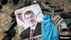 A poster of deposed Egyptian president Mohamed Morsi lies amid debris of a cleared protest camp of his supporters in Cairo August 15, 2013.