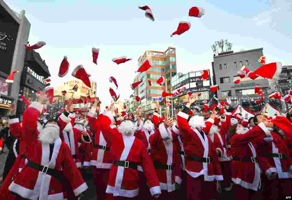 South Korean volunteers in Santa Claus outfits throw Santa hats during a ceremony before the delivery of Christmas gifts in Seoul.