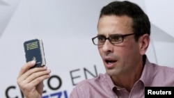 Venezuelan opposition leader and Governor of Miranda state Henrique Capriles holds a copy of the country's constitution while he talks to the media during a news conference in Caracas, Venezuela, April 25, 2016.