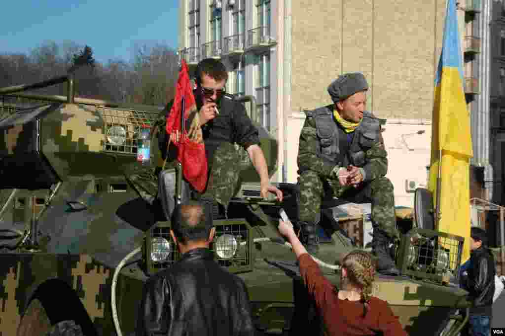 Two men sit atop an armored personnel carrier in downtown Kyiv. (Steve Herman/VOA)