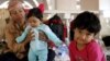 A girl sits with her mother and brother while resting in a mosque in the northern Macedonian city of Kumanovo, on Monday, June 22, 2015. Macedonia changed its asylum law on Thursday to let migrants entering the country illegally avoid jail if they leave t