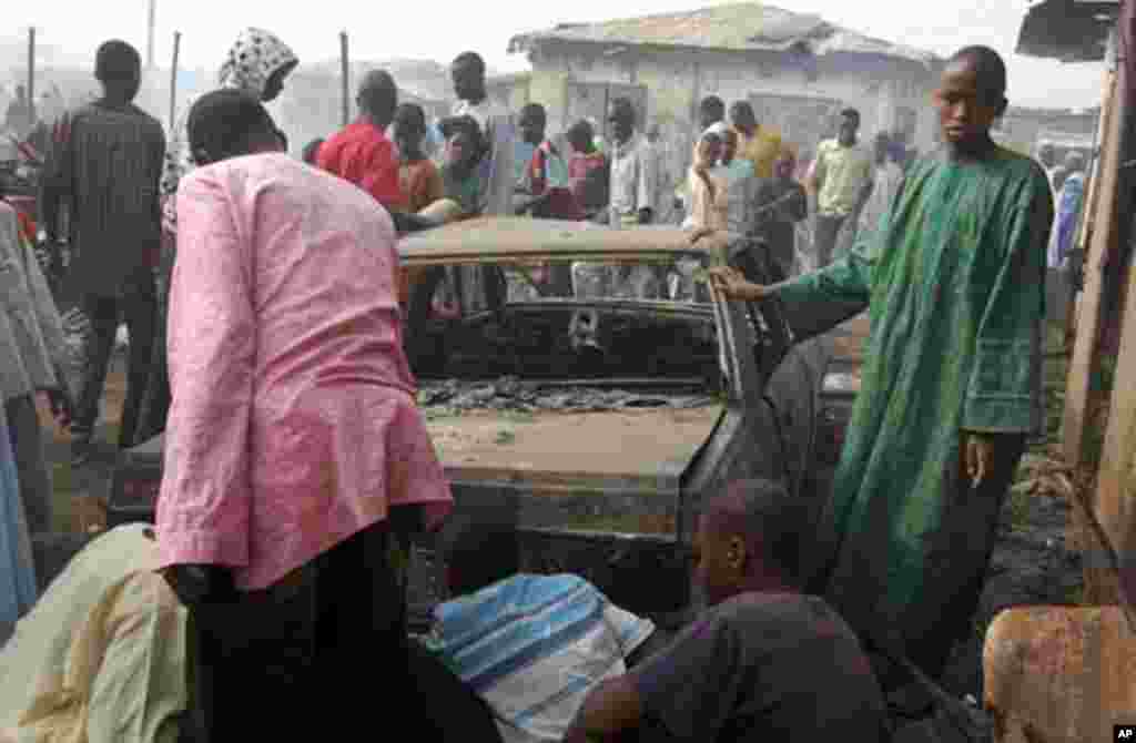 People look at a burnt car after a blast at Gombomru local market on Monday, in Nigeria's northern city Maiduguri February 7, 2012.